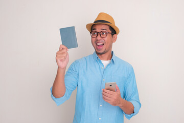 Adult Asian man looking to passport document that he hold with excited expression
