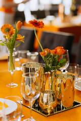 Cutlery, napkins, plates, flowers on an orange table. Table setting. Orange table decor