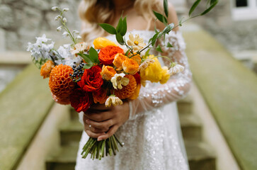 bride in white wedding dress holding a bouquet of bright flowers