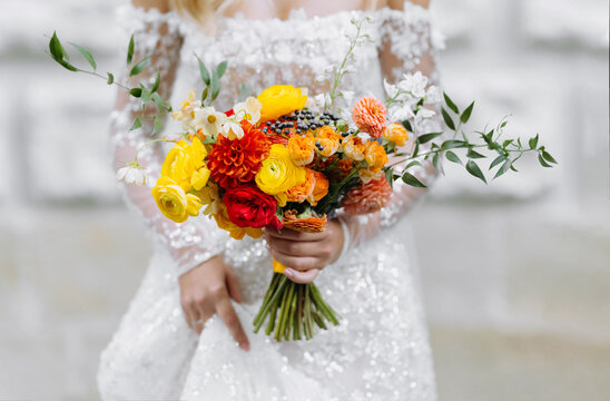 bride in white wedding dress holding a bouquet of bright flowers