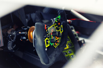 Detailed view of a high-tech racing car steering wheel, gear shift controls and settings. Interior professional race car drivers technology engineering speed in motorsport competition