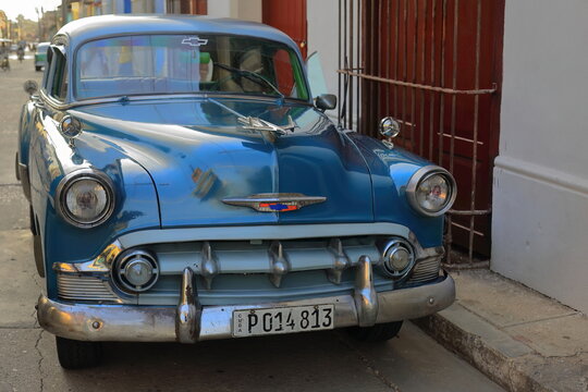 Blue and white almendron car -Chevrolet classic from 1953- parked among colonial-era houses, street in the Plaza Mayor Square area. Trinidad-Cuba-228
