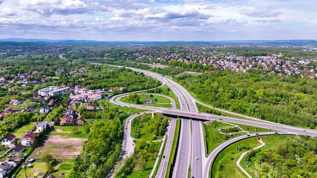 Krakow, Poland. Highway multilevel spaghetti junction on A4 international three lane motorway with entrance and exit ramps, the part of freeway around Cracow with city highway. Aerial video in spring