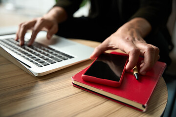 One male hand typing on laptop while another picking phone