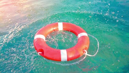 Lifebuoy Floating. Red life buoy over clear blue sea or ocean water background, swimming pool. Floating rescue buoy on the water surface. Inflatable ring floating in the pool. 