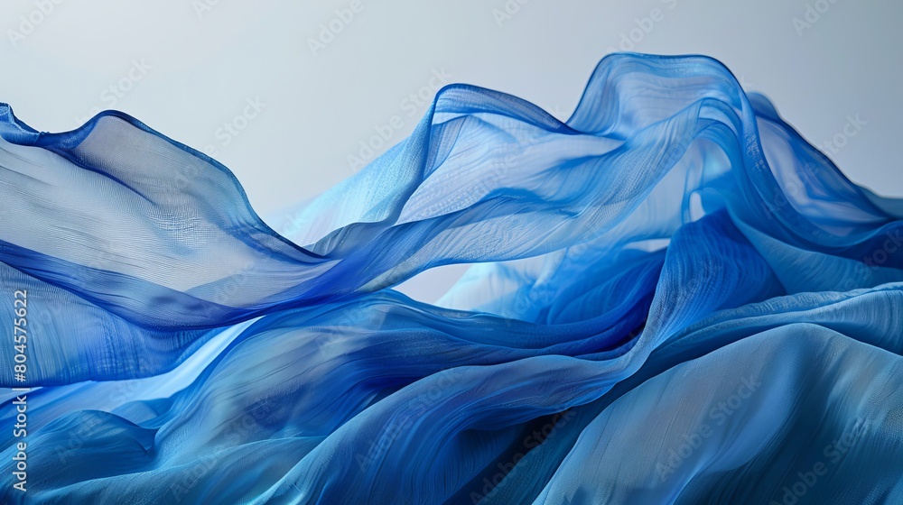 Poster layers of blue textiles arranged in a flowing wave pattern, set against a gray background.