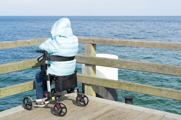 Elderly woman in a wheelchair enjoys the day by the sea. Peace, dreams and memories. Older people,...