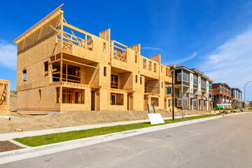 Newly framed construction alongside finished residential units at a luxury townhome and condominium...