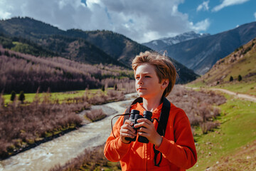 Portrait of boy tourist with binoculars in the mountains