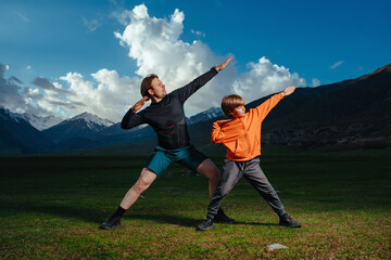 Young man and his son training in the mountains in twilight