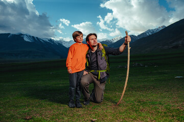 Man hiker with his son standing in the mountains in twilight