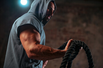 Strong man bodybuilder holds the rope