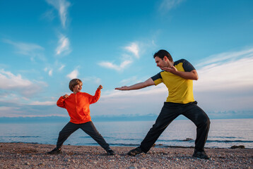 Father and son martial arts training on lake shore