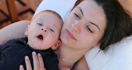 Baby on top of mother yawning looking to camera