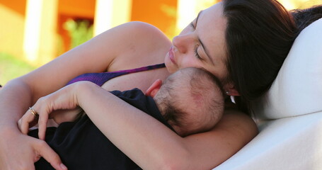 Candid mother holding with baby infant outside by the pool laying down showing care