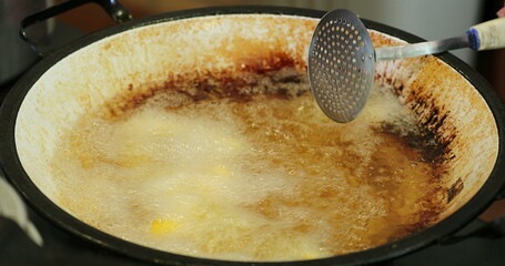 cooking traditional polenta frita inside large frying pan with oil