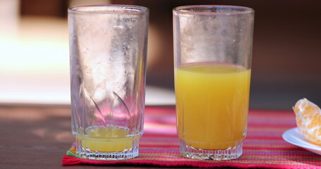 Empty and half full glass of orange juice