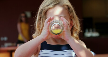 Closeup Little girl drinking orange juice smiling outdoors