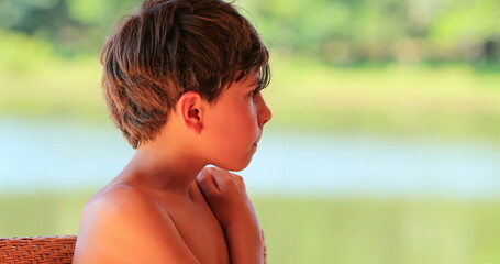 Contemplative little boy outside looking at view