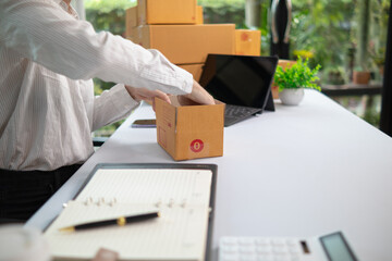 SME business operator is inspecting and packing products into parcel box for delivery company that...