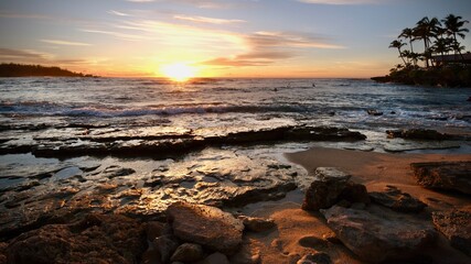 Fototapeta premium Sunset overlooking Turtle Bay in Oahu, Hawaii with surfers awaiting the next wave.
