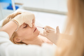 Young adult woman attending procedure of nose contouring
