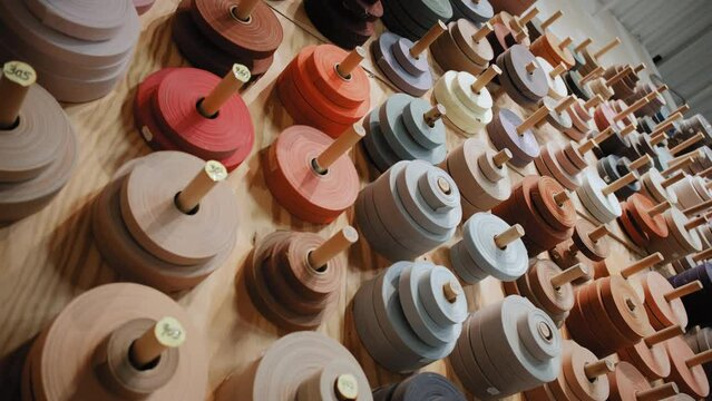 Many colored spools for overlock carpets in a store warehouse. Carpet rolls stacked at store. Move camera view