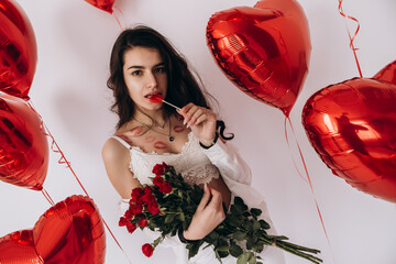 A smiling woman with kisses lipstick is holding a bouquet of red roses, candy, and standing amidst...