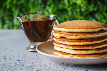 fresh tasty pancakes with maple syrup on a light stone background