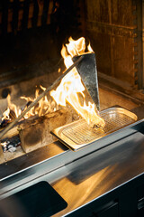 Flambe technique cooking of burning iron triangle pot frying oyster in fireplace