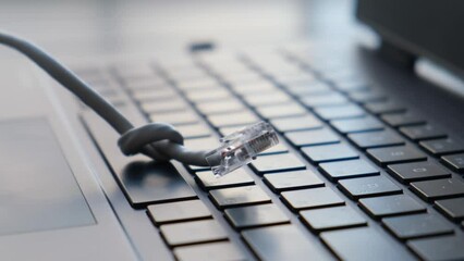 Internet cable tied in a knot on a laptop keyboard, close-up. Concept: Internet shutdown, ban, censorship on the network