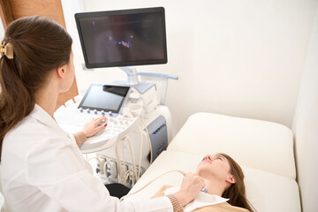 Doctor doing ultrasound scan of woman thyroid gland and they looking at monitor