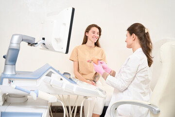 Female gynecologist showing uterus model to young smiling european woman