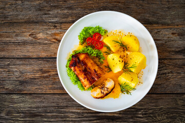 Baked rabbit saddle and vegetable salad on wooden table
