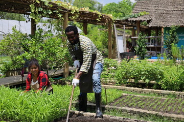 Happiness black family study learning to prepare the soil before planting vegetables.