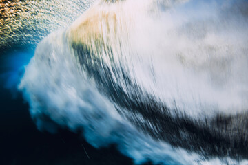 Barrel wave crashing in ocean with sunset sunlight. Underwater view of surfing wave with long...