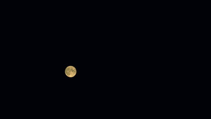 Full moon, moon is moving across sky. Moon light up in night dark black sky. Timelapse.