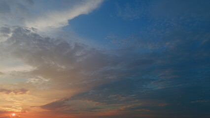 View of yellow sun setting in orange sky with dark clouds. Timelapse.