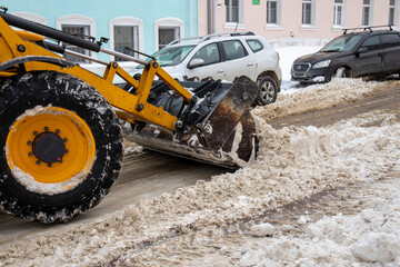 . A yellow front loader, equipped with a large black bucket attachment, is actively engaged in...