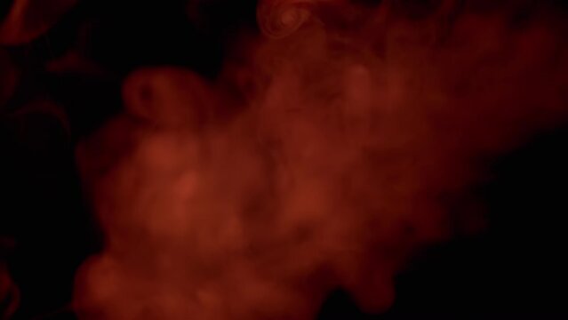 Explosion of Red Smoke or Vapor on Black Blurred Background. Abstract. Side view. Flash. Soft puffs of smoke or steam mix chaotically on empty space. Flash. Passing smoke, tail. Particle explosion.