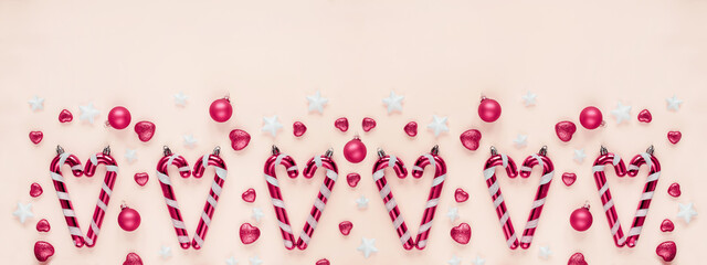 Christmas themed arrangement with candy canes, pink balls, star decorations pastel pink background