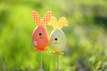 Easter background. Multi-colored Easter eggs - bunnies on the grass in the garden