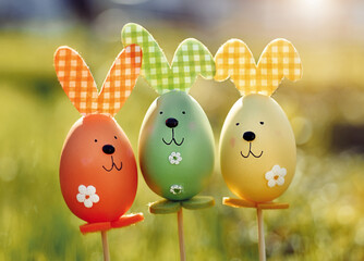 Easter background. Multi-colored Easter eggs - bunnies on the grass in the garden