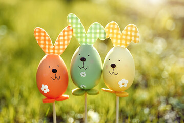 Easter background. Multi-colored Easter eggs - bunnies on the grass in the garden