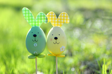 Easter background. Multi-colored Easter eggs - bunnies on the grass in the garden