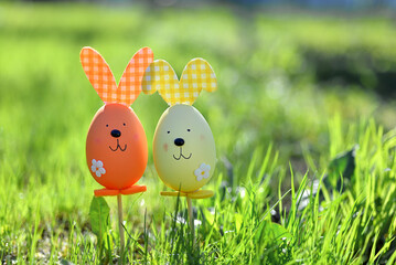 Easter background. Multi-colored Easter eggs - bunnies on the grass in the garden