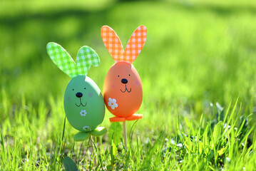 Easter background. Multi-colored Easter eggs - bunnies on the grass in the garden