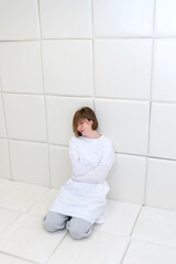 Young frustrated girl in a straitjacket is in an isolated white room in a mental hospital	