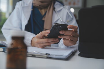 Consultation Online. Unrecognizable doctor using smartphone at workplace, messaging with patient,...