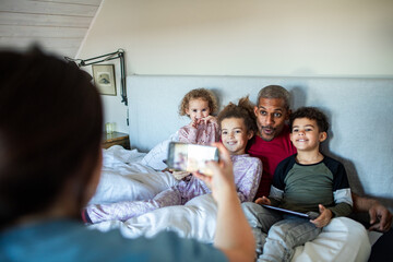 Happy multiracial family posing for a group photo in bed